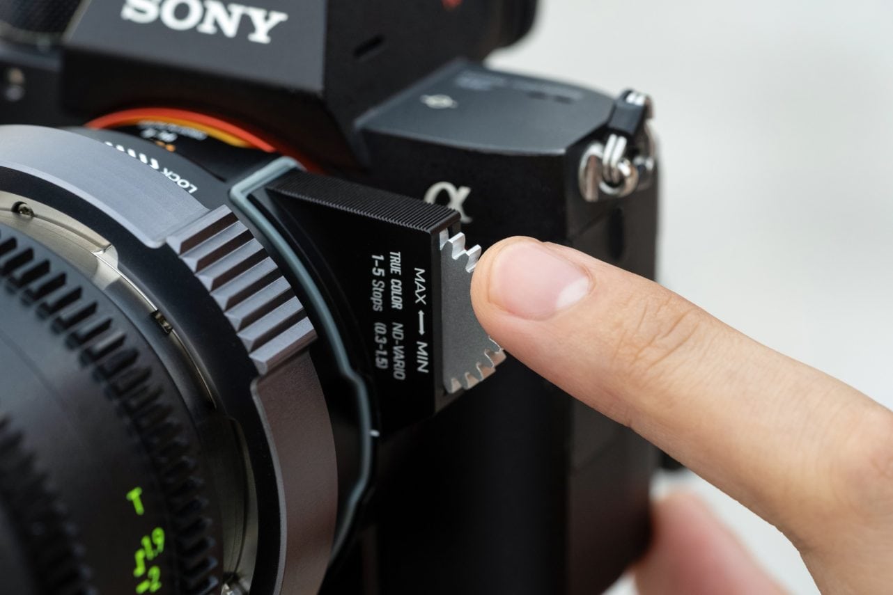Finger turning the gear of a True Color ND-VARIO drop-in filter in the NiSi PL Mount Adapter on a Sony camera